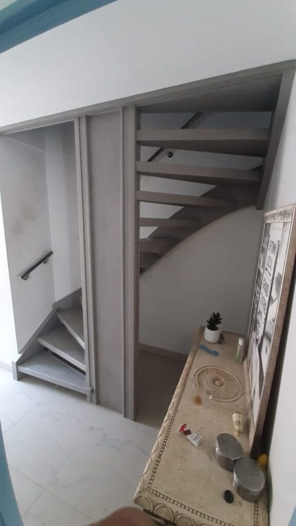 Open trap in lichtgrijze houtlook met zwarte leuning, gezien vanaf de overloop